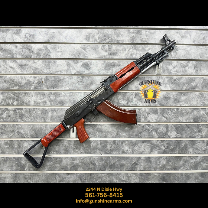 Transferable AK machine gun, Hard Times Armory AKS Spiker, right side on the wall with folding stock extended, Bakelite handguards and pistol grip, and 30-round magazine